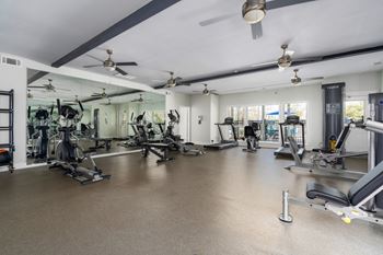 The fitness center boasts natural light, ceiling fans and a variety of equipment.